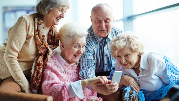 a group of elderly friends looking at a mobile phone