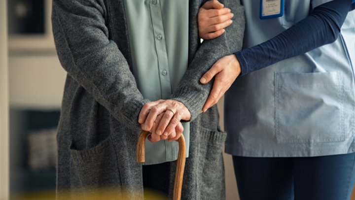 a senior lady holding hands with a nurse